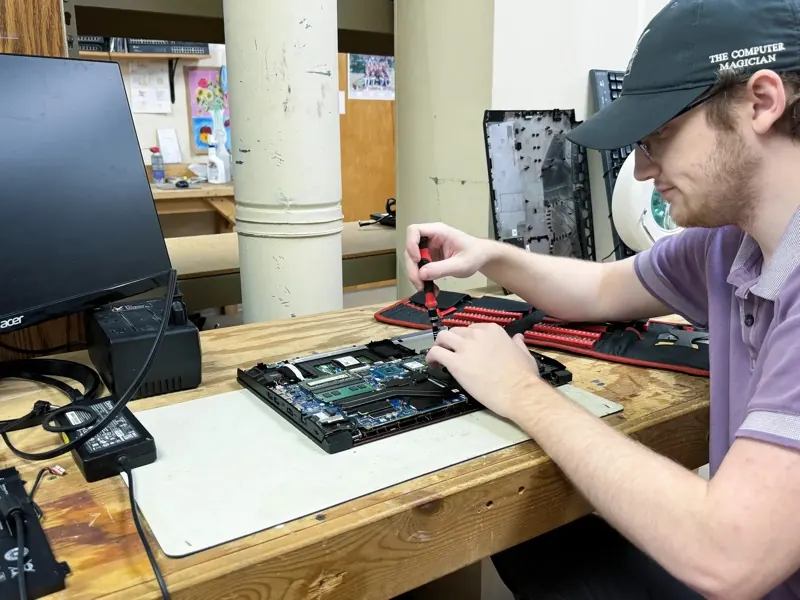 The Computer Magician technician repairing a laptop at the service bench